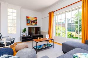 uma sala de estar com um sofá e uma televisão em Jacuzzi, garden, pool & barbecue beach House, 15mn from Lisbon center em Oeiras