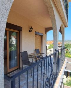 einen Balkon eines Hauses mit 2 Stühlen und einem Tisch in der Unterkunft Apartmani Talija 3 i 4 Sokobanja in Sokobanja