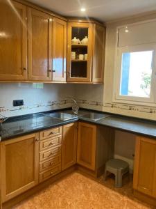 a kitchen with wooden cabinets and a sink and a window at GRANDIOSO CHALET EN CASTELL DE POBLA MONTORNES in Pobla de Montornés