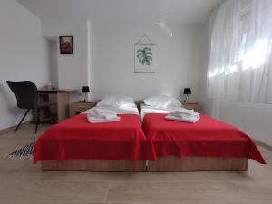 クラリェヴィツァにあるApartment Deeranaeiのデスク付きの客室で、赤いカバー付きのベッド2台が備わります。