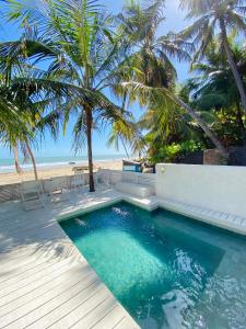 a swimming pool next to a beach with palm trees at Nordestina Casa de Mar in Icaraí