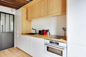 a kitchen with white cabinets and a stove top oven at Studio 2P renovated rue des Archives Marais Clim 4 in Paris