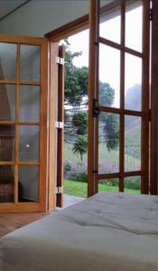 - une chambre avec une grande porte en verre et un lit dans l'établissement Casa flores do campo, à Campos do Jordão
