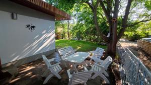un patio con sillas blancas, una mesa y un árbol en Captain's Cottage 110m2, near Sopot, beaches, with a garden, grill & free parking en Gdansk