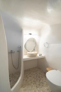 a bathroom with a sink and a mirror and a toilet at Spilia Caves Santorini in Akrotiri