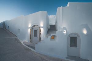 a white building with stairs and doors on it at Spilia Caves Santorini in Akrotiri