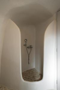 a bathroom with a faucet in a white wall at Spilia Caves Santorini in Akrotiri