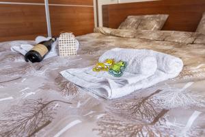 a bed with two towels and a bottle of wine at Duma Apartmani Vrnjačka Banja in Vrnjci