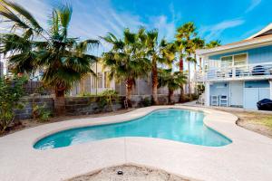 a swimming pool in front of a house with palm trees at Lazy Seagull Beach House in South Padre Island