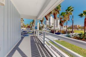 un balcón con palmeras y una valla en Lazy Seagull Beach House, en South Padre Island