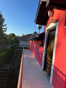 a red building with a walkway leading to a door at Guest Radic Room in Palić