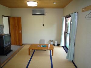 a living room with a table and a tv at Tabi No Yado Harusame in Kumano