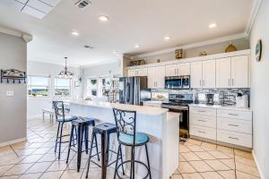 a kitchen with white cabinets and bar stools at Gulf Breezes Entire Home in Port Aransas