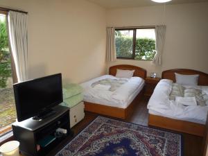 a room with two beds and a flat screen tv at Tabi No Yado Harusame in Kumano