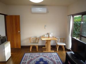 a living room with a table and chairs and a television at Tabi No Yado Harusame in Kumano