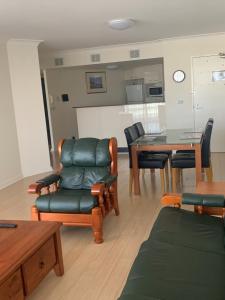 sala de estar con sillas de cuero y mesa en Northpoint Apartments, en Port Macquarie