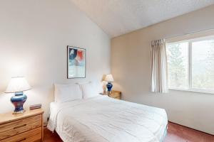 a bedroom with a large white bed and a window at Crestview 70 in Mammoth Lakes