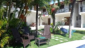 a yard with chairs and a table and palm trees at Casa - suites com varanda in Conde