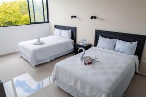 Un dormitorio con dos camas con un cisne. en Hotel & Suites Yuca Ville Siglo XXI, en Mérida