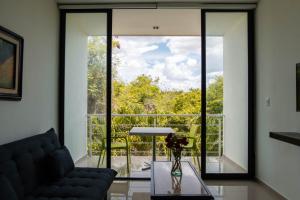 a living room with a couch and a large glass window at Hotel & Suites Yuca Ville Siglo XXI in Mérida