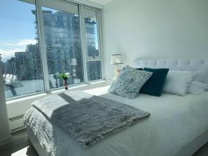 a bed in a bedroom with a large window at Downtown 3br/2ba+Views+Skytrain+Free Parking in Vancouver