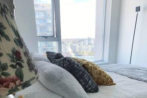 a bedroom with pillows on a bed with a window at Downtown 3br/2ba+Views+Skytrain+Free Parking in Vancouver