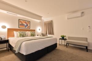 a bedroom with a large bed and a chair at Best Western Newmarket Inn & Suites in Auckland