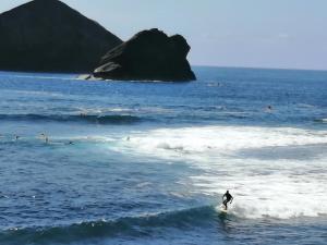a person riding a wave on a surfboard in the ocean at Casa Dos Mosteiros in Mosteiros