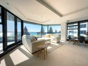 a living room with a couch and a table at Mount Eleven Fabulous Sea Views in Mount Maunganui