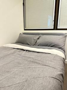 uma cama num quarto branco com uma janela em 2 Bedroom Apartment @ Grenfell Street em Adelaide