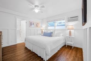 a white bedroom with a bed and a ceiling fan at Newport Coastal Compound in Newport Beach