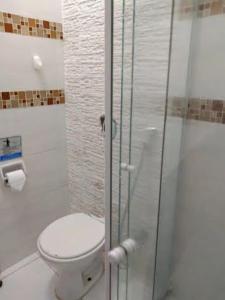 uma casa de banho com um WC e uma cabina de duche em vidro. em Loft Aconchegante no Centro de Niterói! em Niterói