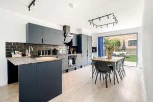 a kitchen with black cabinets and a table with chairs at Urban Luxury 4-Bed Retreat Explore And Relax in London