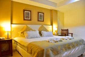 1 dormitorio con 1 cama grande y paredes amarillas en Hotel Astur en Salta