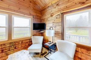 Modern Log Chalet - Upper Level في Montgomery: غرفة بها كرسيين وتلفزيون ونافذتين