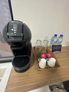 a coffee maker on a table with cups and water bottles at Audaar Tech Suítes - Aeroporto de Congonhas in Sao Paulo
