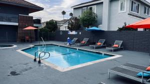 uma pequena piscina com cadeiras e uma casa em OC Hotel em Costa Mesa