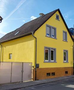 una casa amarilla con dos ventanas y una valla en Ferienwohnung Popp, en Erzhausen