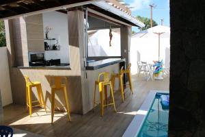 patio z żółtymi krzesłami i basenem w obiekcie Guarajuba Sereia House w mieście Guarajuba