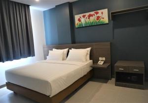 a bedroom with a large bed and a night stand at Ayani Hotel Banda Aceh in Banda Aceh