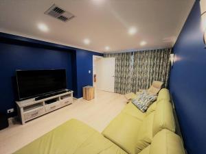 a living room with a couch and a flat screen tv at West Beach House in Esperance