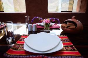 einen Tisch mit weißen Tellern und Blumen darauf in der Unterkunft Rumi Lodge Pisac in Pisac