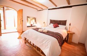 a bedroom with a large bed with white sheets at Rumi Lodge Pisac in Pisac