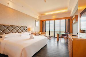 a hotel room with a large bed and a table at Four Points by Sheraton Hainan, Sanya in Sanya