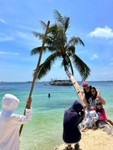 un gruppo di persone seduti sotto una palma su una spiaggia di Lazy Dog Bed & Breakfast a Boracay