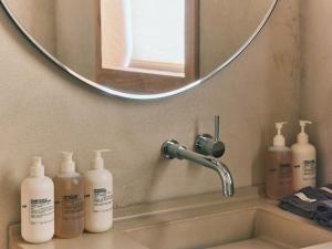 a bathroom sink with four bottles of soap and a mirror at guesthouse by good neighbor in Baltimore