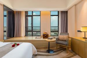 a hotel room with a bed and a chair and windows at 佛山金美域林禧酒店 in Foshan