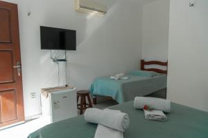 a room with two beds and a flat screen tv at Pousada Águas Claras in Jijoca de Jericoacoara