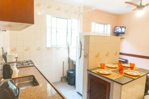 una cocina con nevera y algunos platos en una encimera en Apartamentos Incríveis Primeira Quadra Mar WiFi en Ubatuba