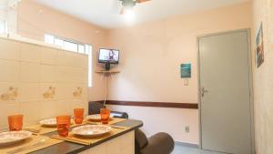 um quarto com uma mesa e uma televisão na parede em Apartamentos Incríveis Primeira Quadra Mar WiFi em Ubatuba